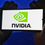 Hands holding a smartphone showing the NVIDIA logo on a bright screen.